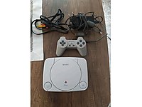 Sony ps 1 ve ps 1 slim yanında 2 kol ve görüntü kabloları vardır